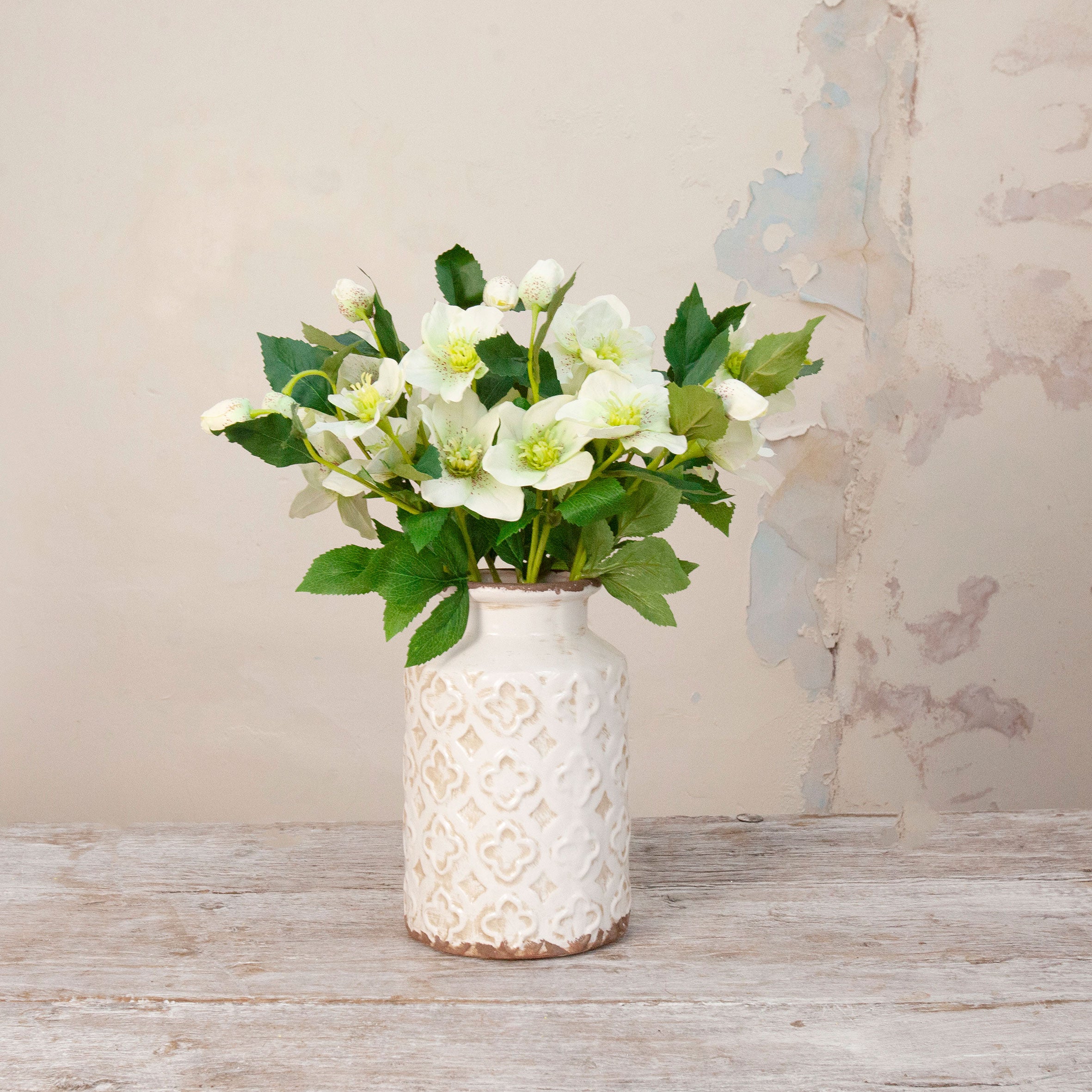 Artificial Hellebore Stems with delicate white flowers, soft green centres, buds and realistic green foliage displayed in a textured white ceramic vase