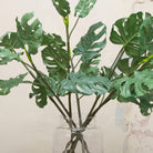 Close up of artificial green tropical monstera leaf stems 