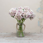 Artificial lilac hydrangea stems displayed in a vase, showcasing a large clustered bloom with gentle lavender tones and natural-looking foliage.”