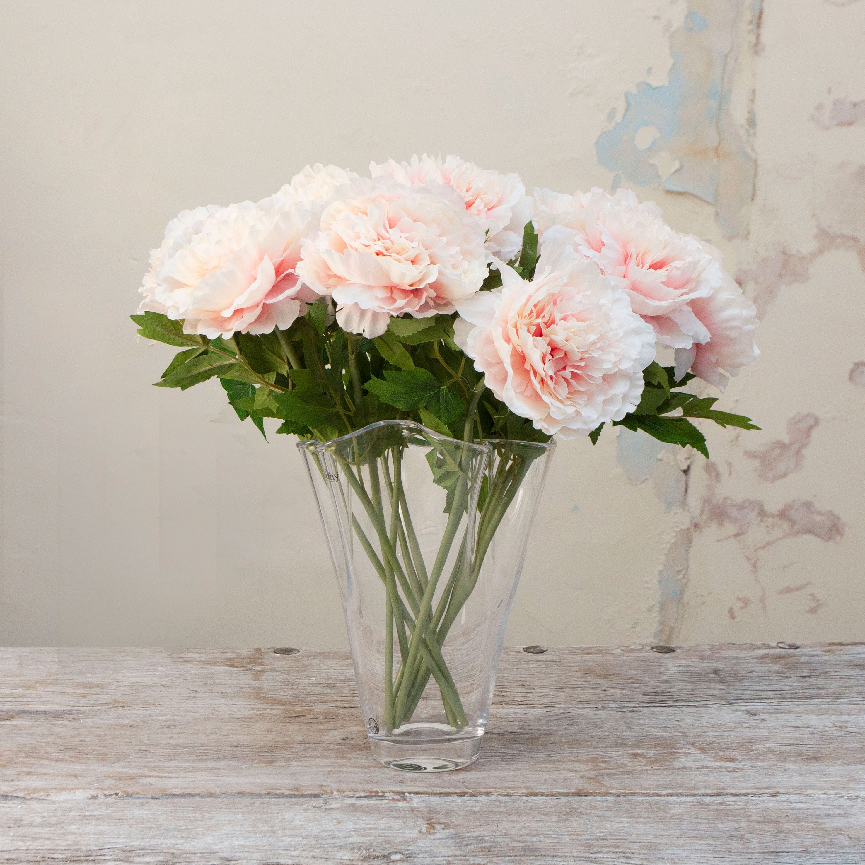 Artificial pale pink with peach toned open Peony Stems displayed in a glass vase 