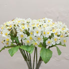 Close-up of artificial white blossom stems with yellow centres and green leaves