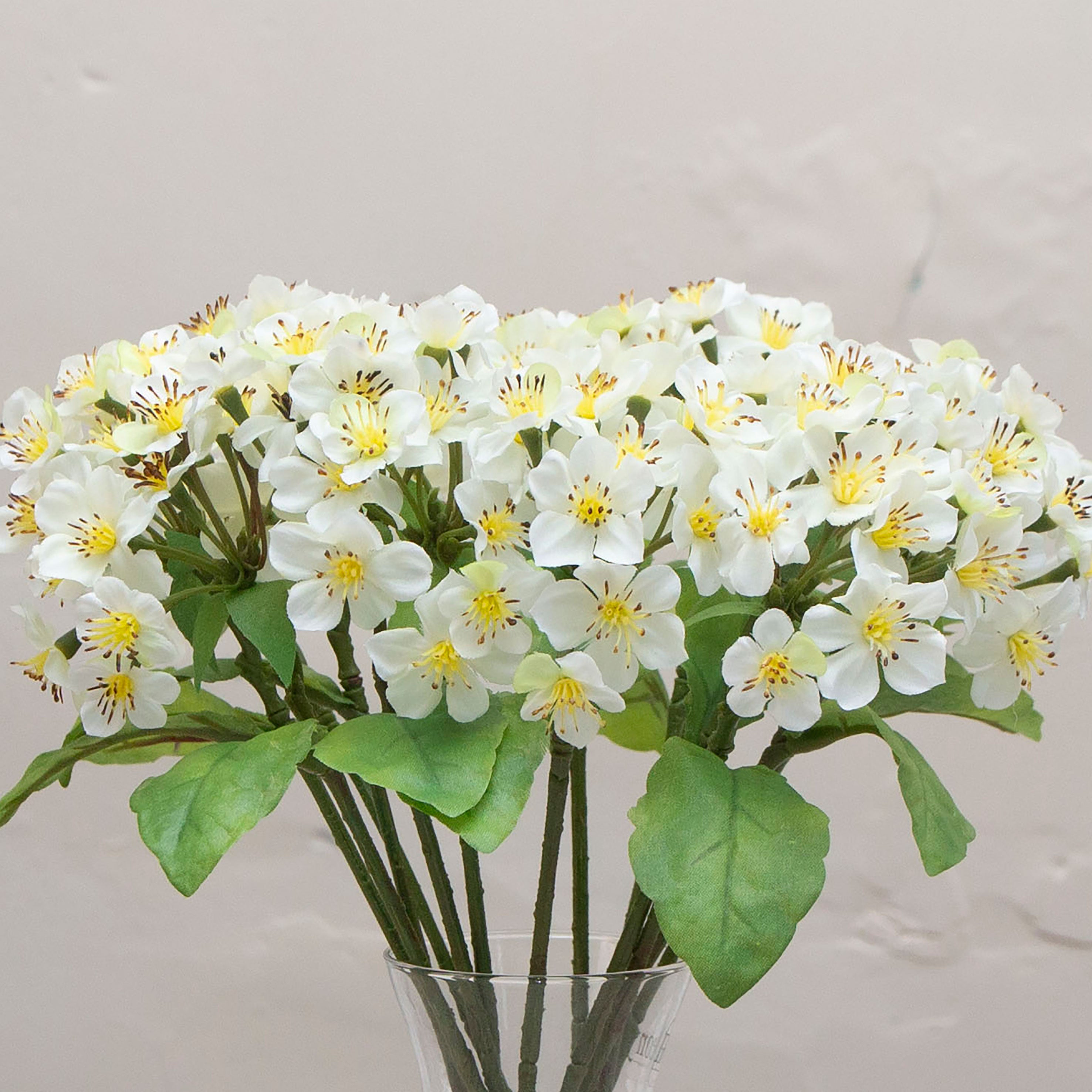 Close-up of artificial white blossom stems with yellow centres and green leaves