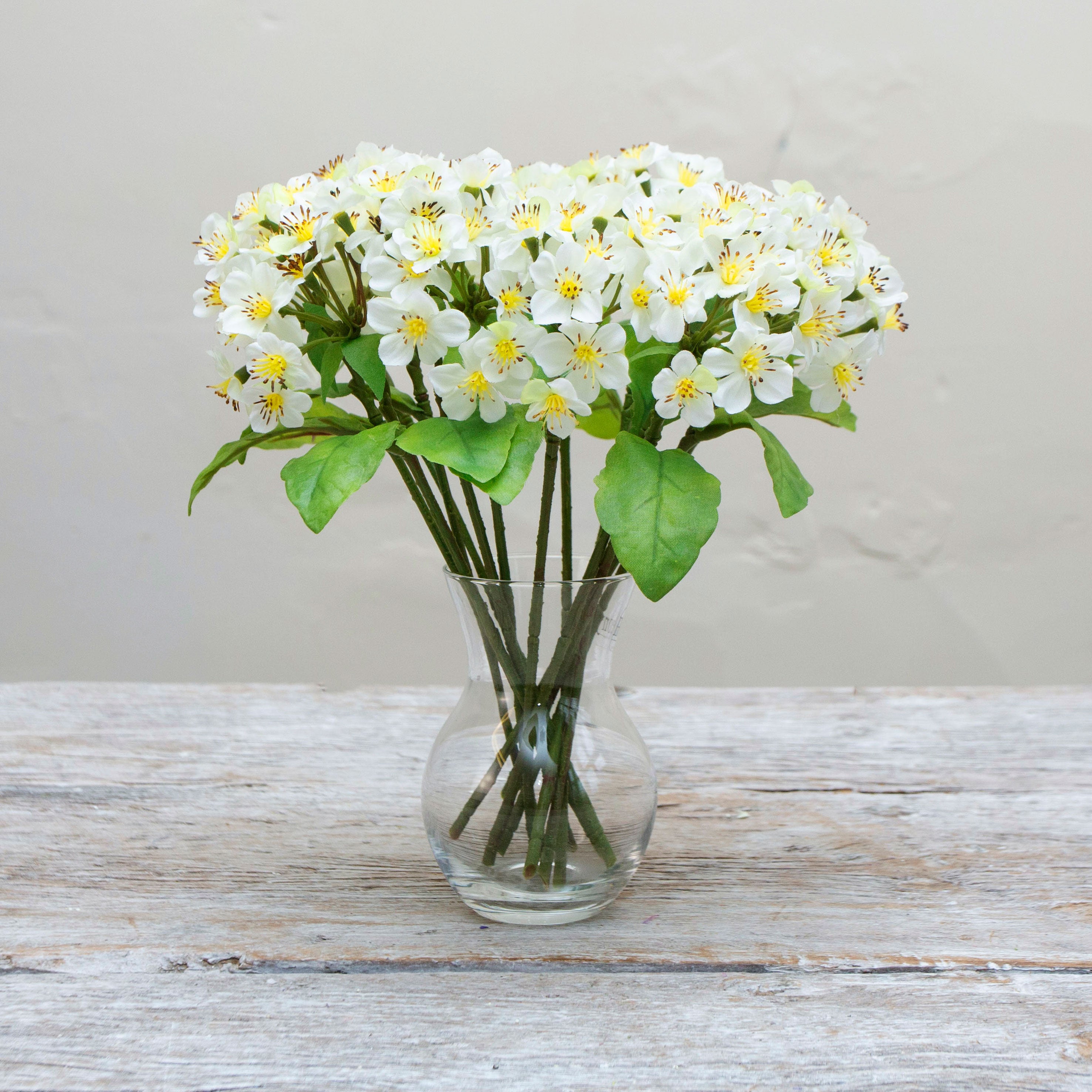 Artificial White Blossom pick stems with yellow centres displayed in a glass vase 