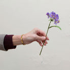 Hand holding artificial purple Blossom pick stem with yellow centres 