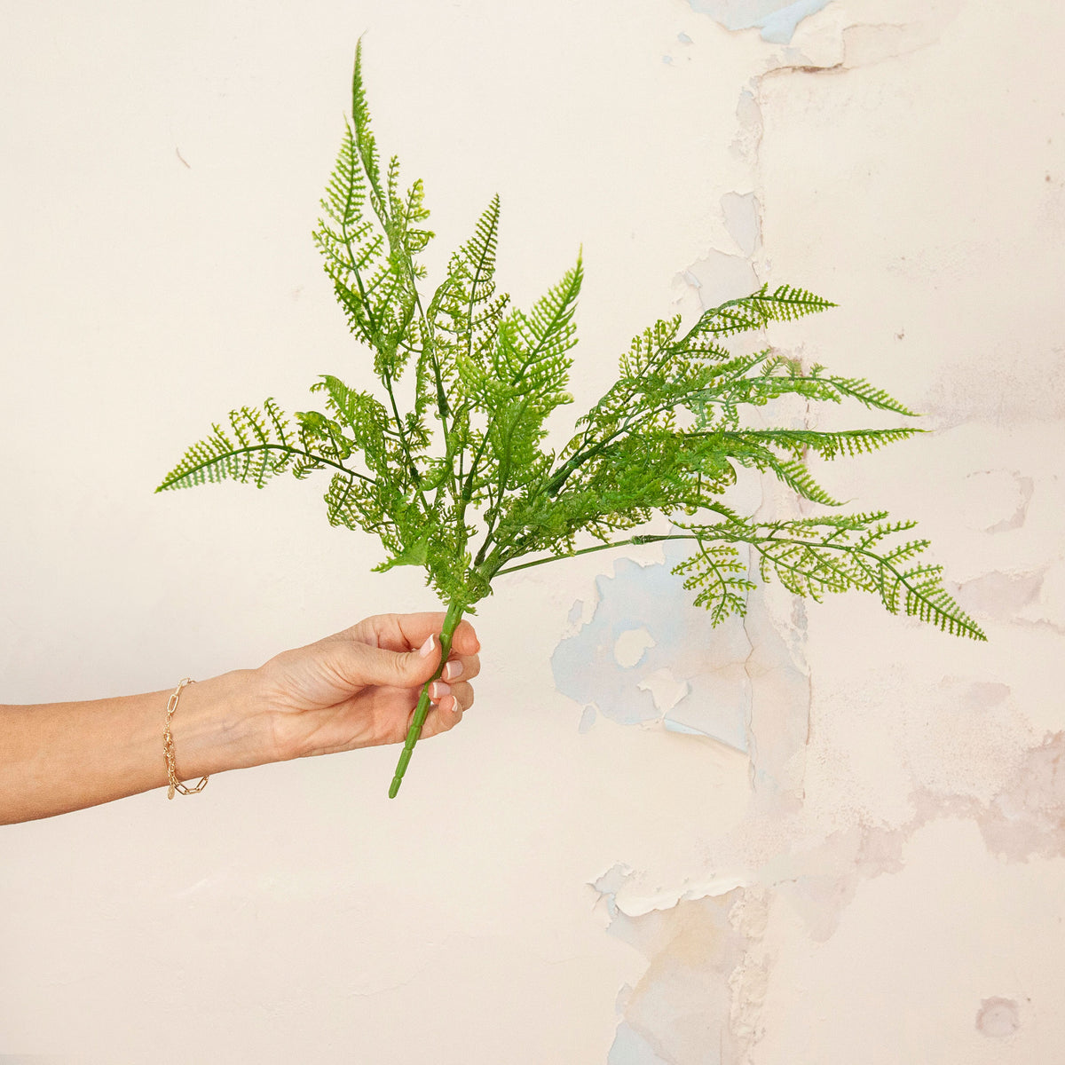 Hand holding Artificial Fern Bush Stem with lush, feathery green fern foliage 
