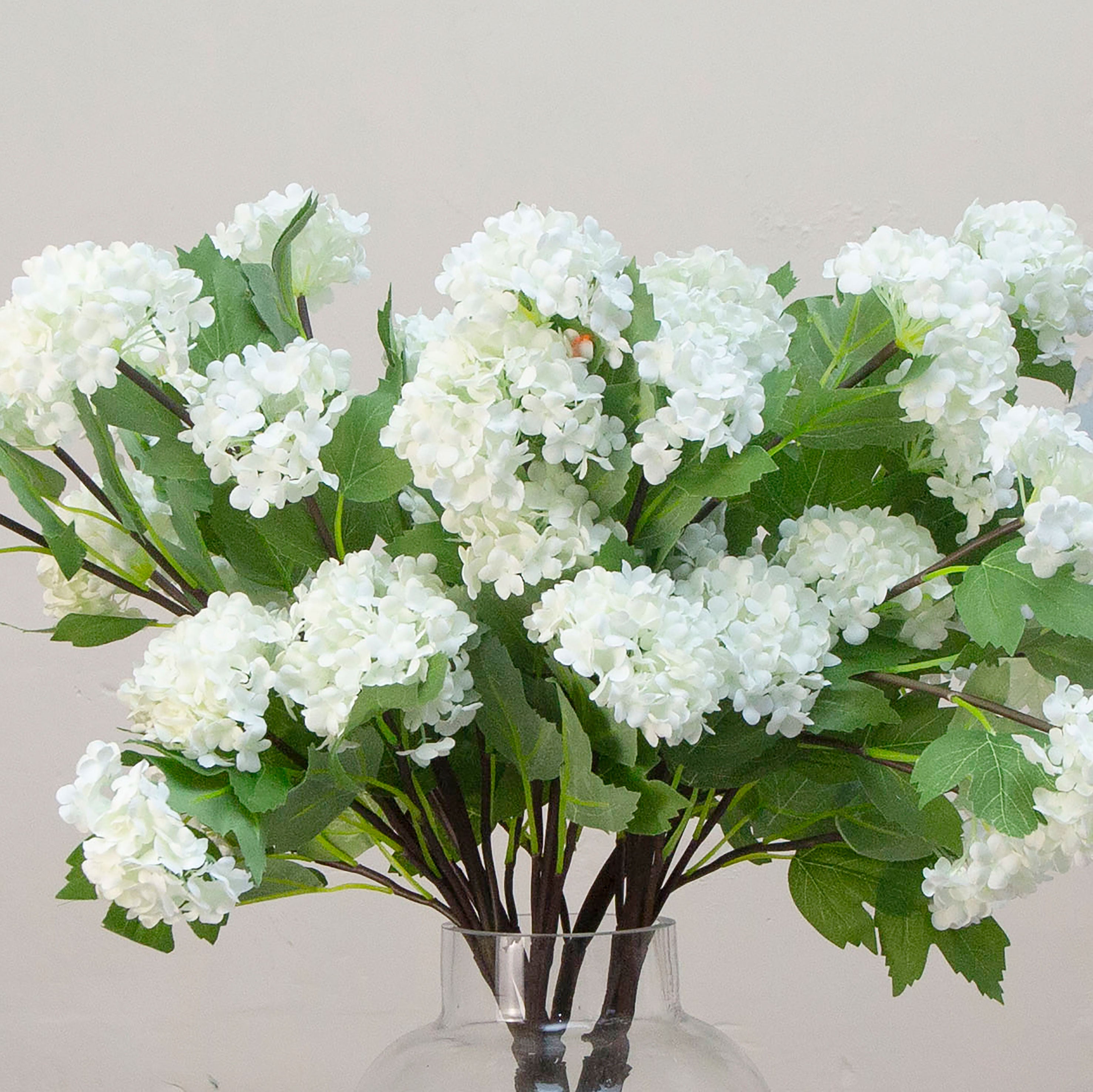 Close up of artificial white snowball stems with green leaves 