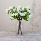 Artificial white snowball stems with green leaves displayed in vase 