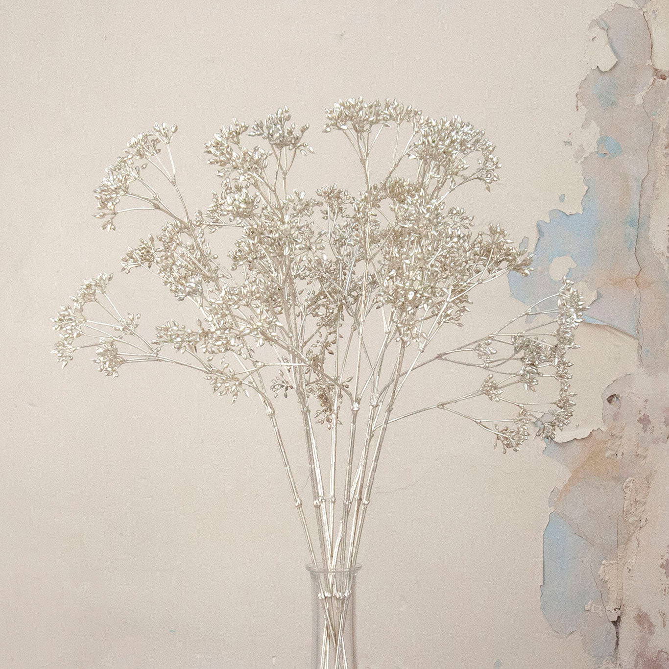 Close up of Artificial Foliage Stems with delicate branching flowers and fine botanical detailing displayed in a clear glass bud vase