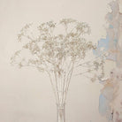 Close up of Artificial Foliage Stems with delicate branching flowers and fine botanical detailing displayed in a clear glass bud vase