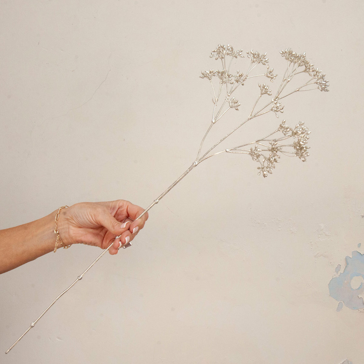 Hand holding Artificial Foliage Stems with delicate branching flowers 