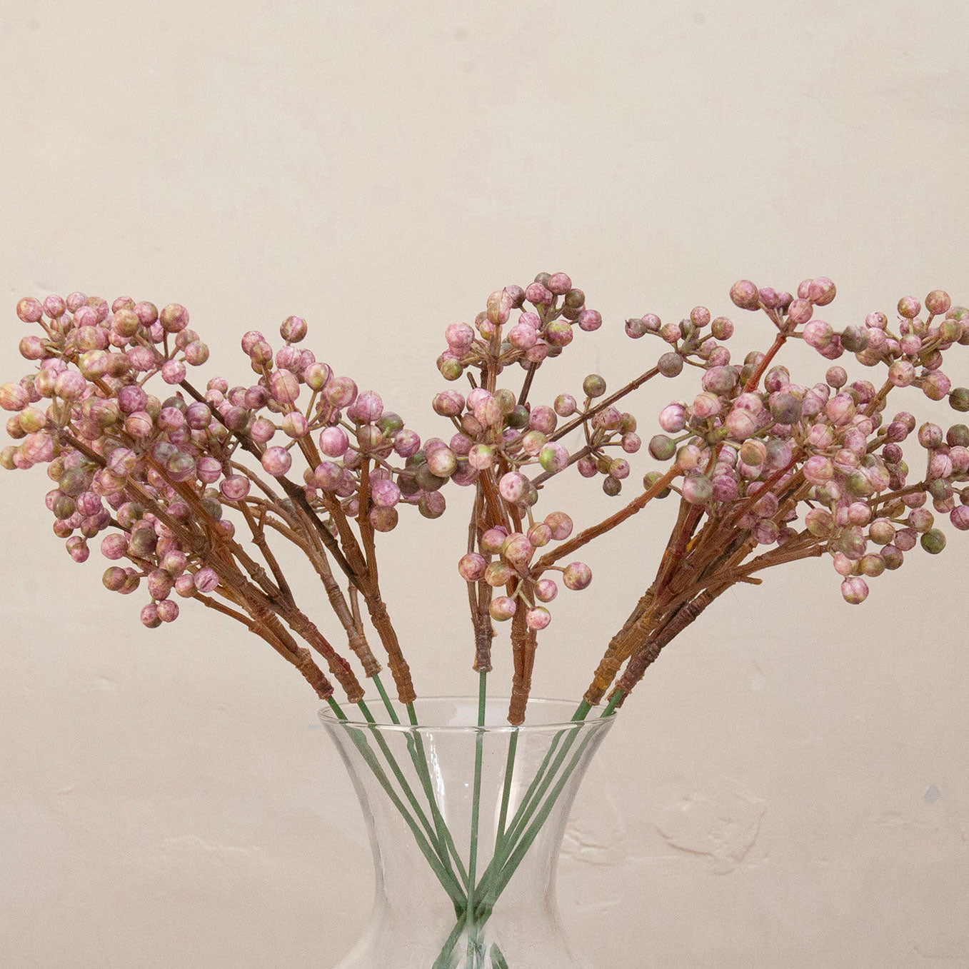 Close up of Artificial Berry Pick Stems with clusters of soft pink and mauve berries on natural brown branches displayed in a clear glass vase