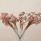 Close up of Artificial Berry Pick Stems with clusters of soft pink and mauve berries on natural brown branches displayed in a clear glass vase