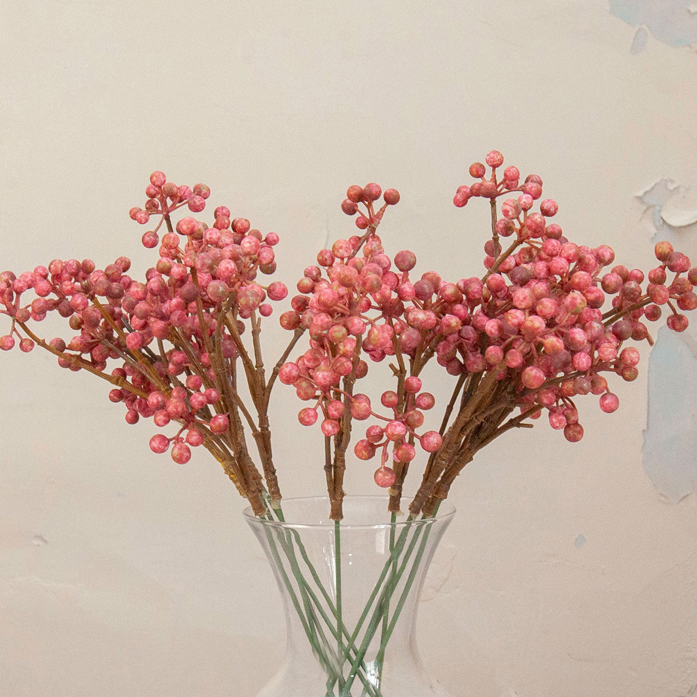 Close up of Artificial Berry Pick Stems with abundant clusters of vibrant pink berries on natural brown branches displayed in a clear glass vase