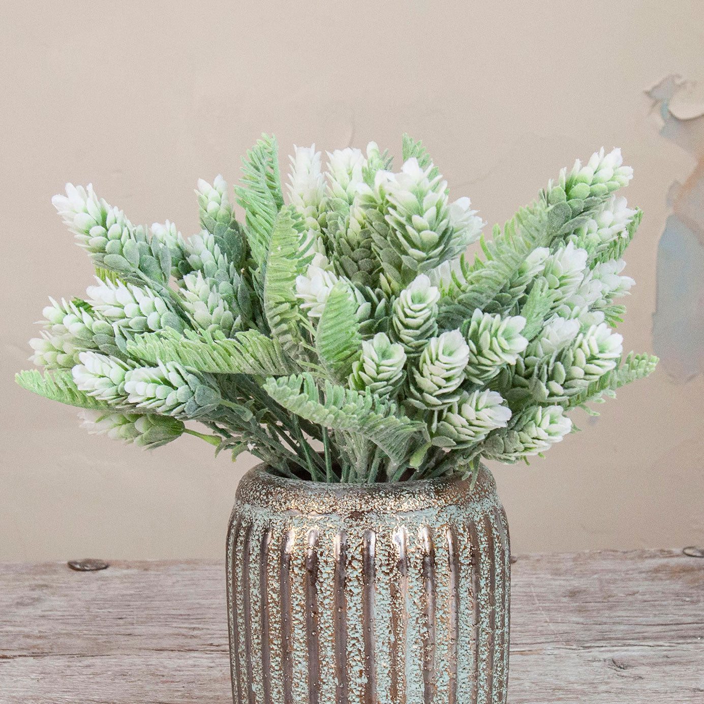 Close up of Artificial Pine Cone Fern Flocked Stems with frosted green fern foliage, soft white flocked tips and pine cone detailing displayed in a textured metallic vase