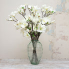 Long stemmed artificial white magnolia on brown stems displayed in vase 