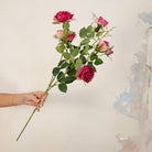 Hand holding Artificial Julie Rose Spray Stem with vibrant pink rose blooms, soft pink buds and realistic green foliage 