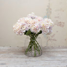 Artificial large headed hydrangeas stems with pale lilac and cream mixed petals displayed in vase 