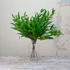 Artificial green long leaf eucalyptus stems with seeds displayed in vase 