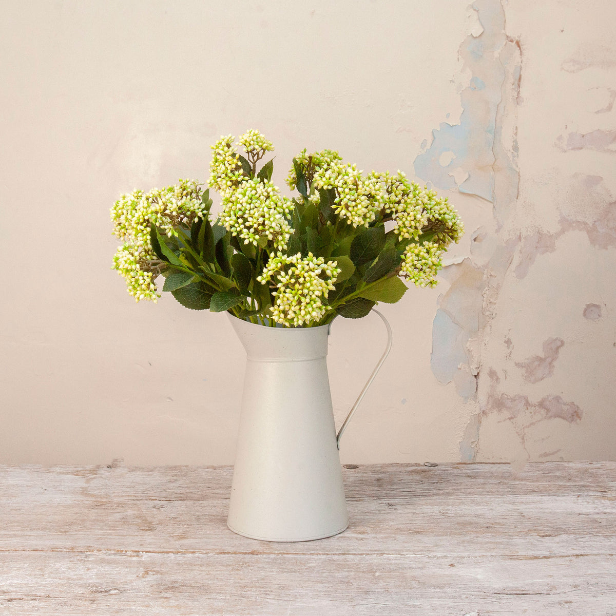 Artificial Berry Stems with clusters of cream and pale green berries, dark green leaves and natural brown branches displayed in a white metal jug