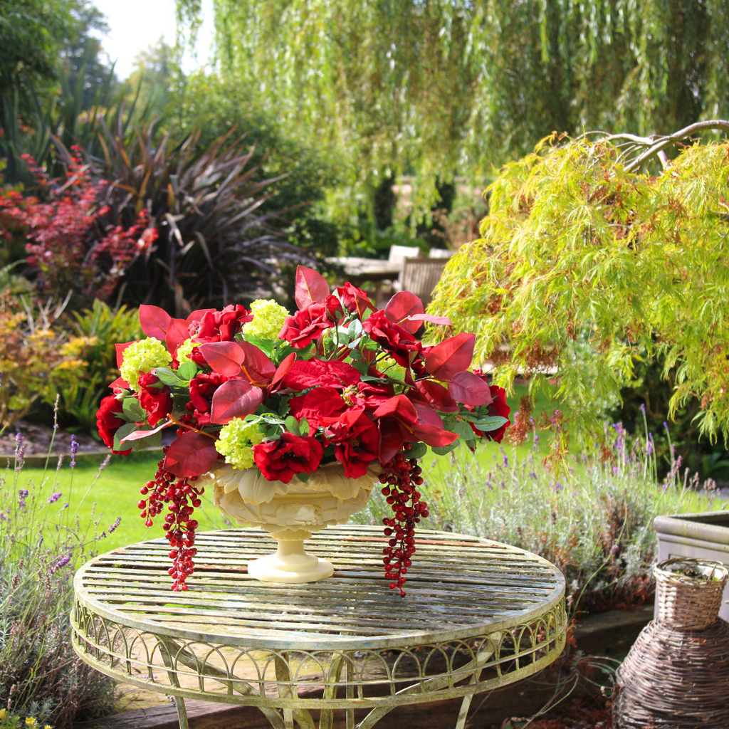 Red Roses and Poinsettias in a Grape Leaf Resin Footed Vase Outside