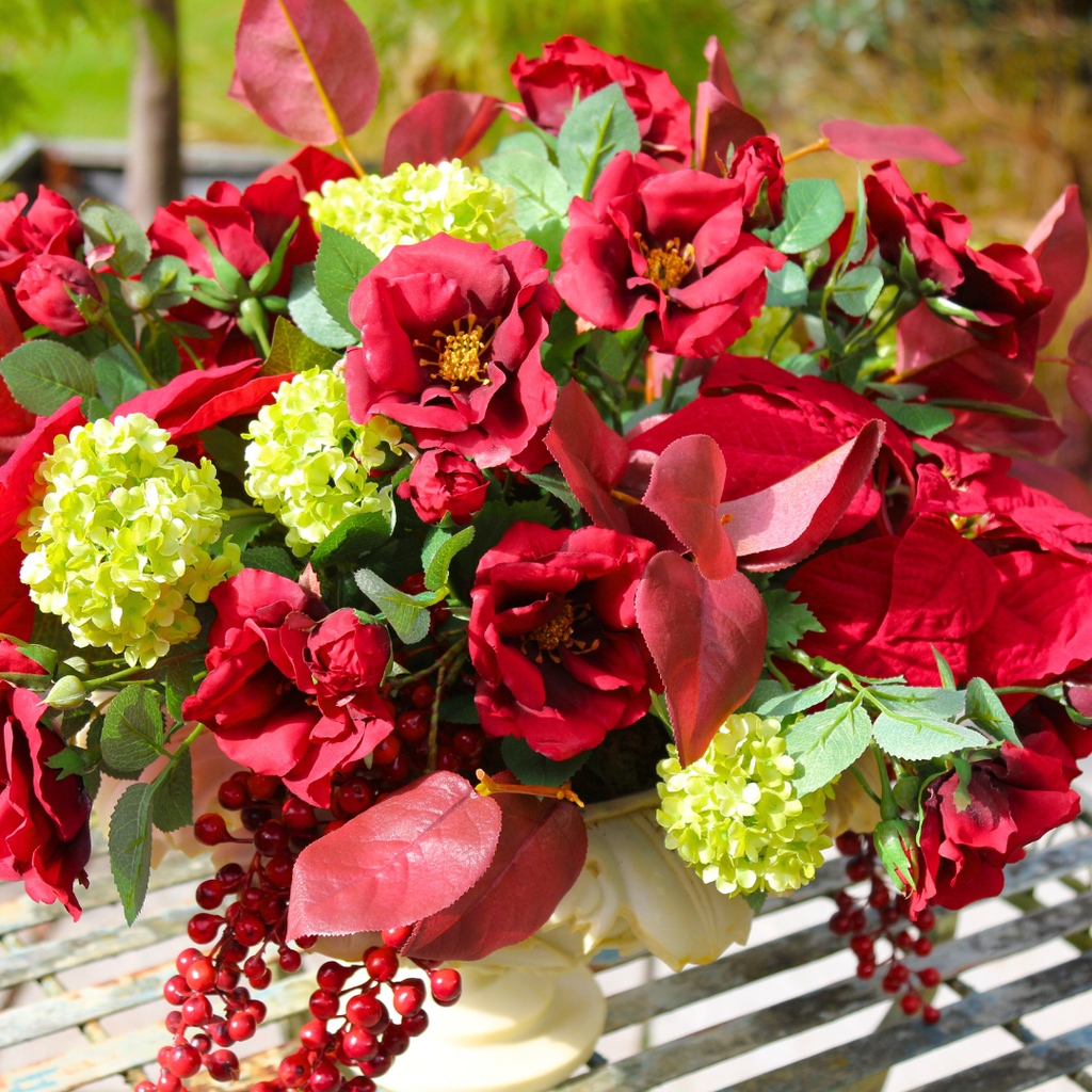 Red Roses and Poinsettias in a Grape Leaf Resin Footed Vase Outside Close up 