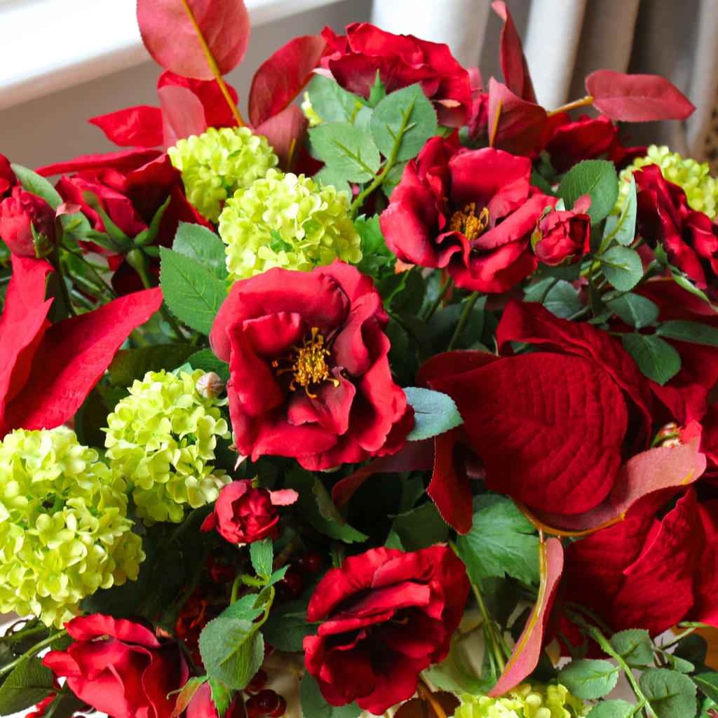 Red Roses and Poinsettias in a Grape Leaf Resin Footed Vase Lifestyle Close up 