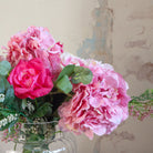 Artificial hydrangea and rose arrangement with soft greenery displayed in a large clear glass Chelsea vase,