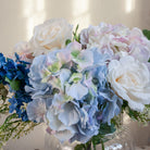 Artificial hydrangea and rose arrangement with soft greenery displayed in a large clear glass Chelsea vase,