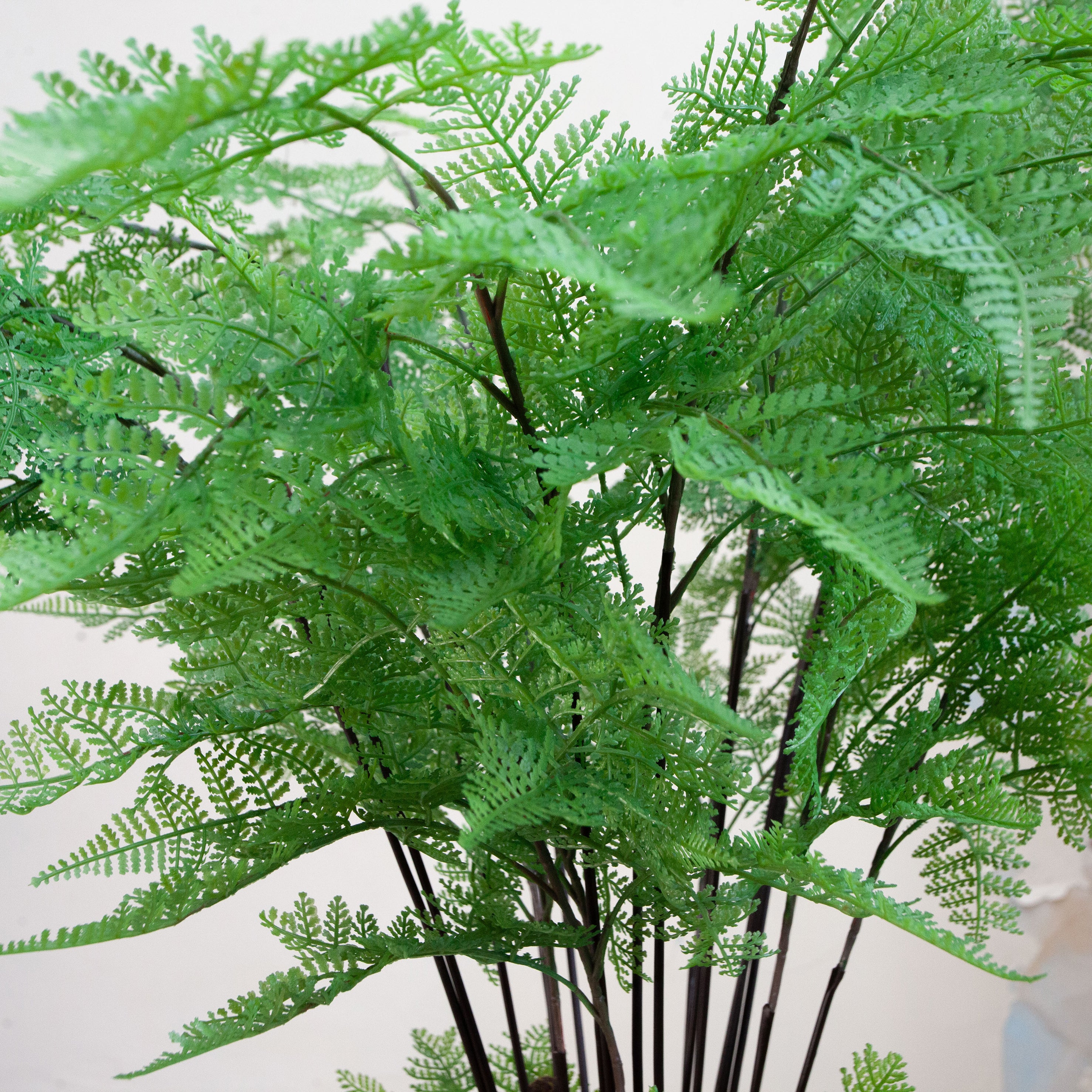 Artificial fern arrangement with lush green fronds displayed in a decorative engraved pot