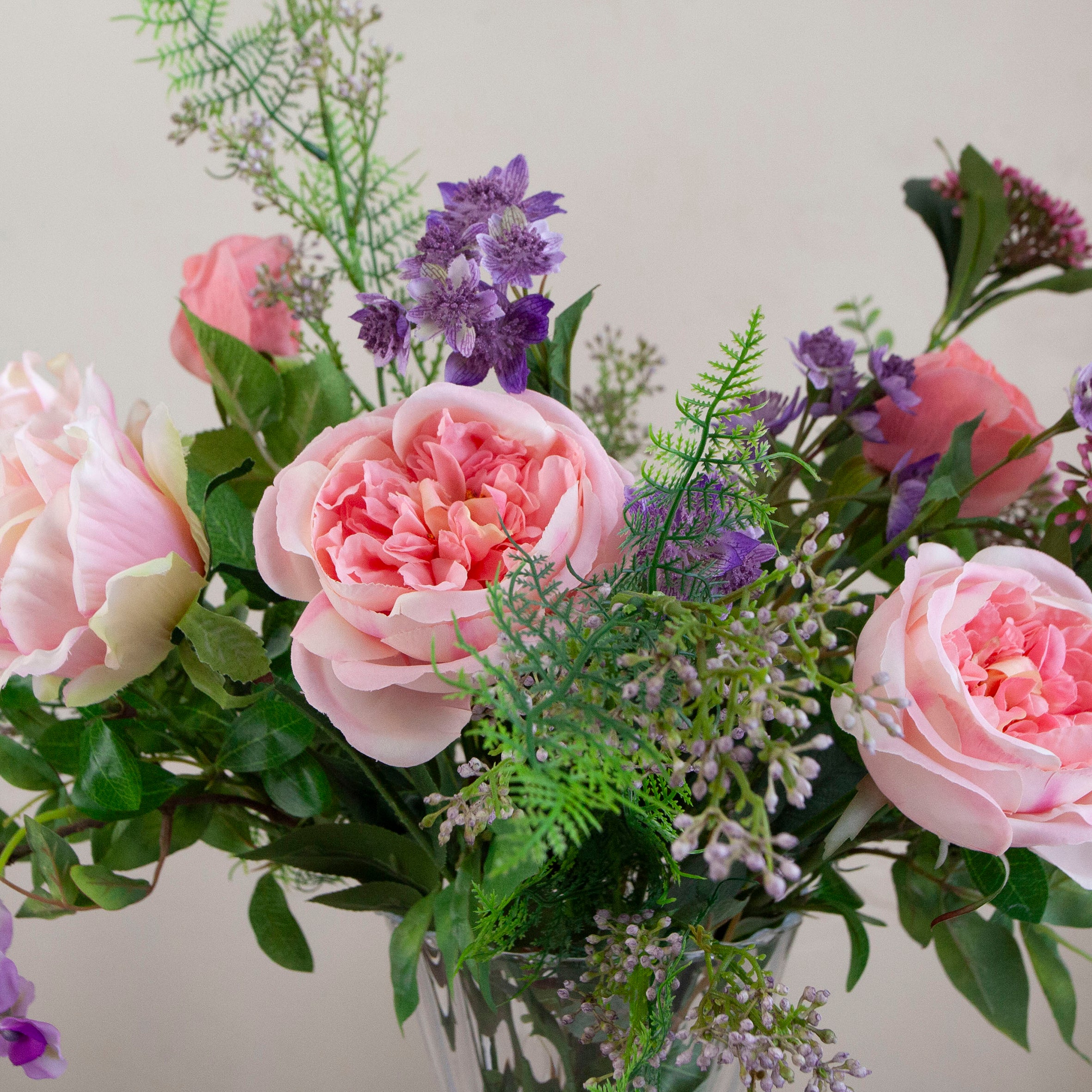 Artificial bouquet of pale pink roses, lavender wisteria, and astrantia with soft greenery,