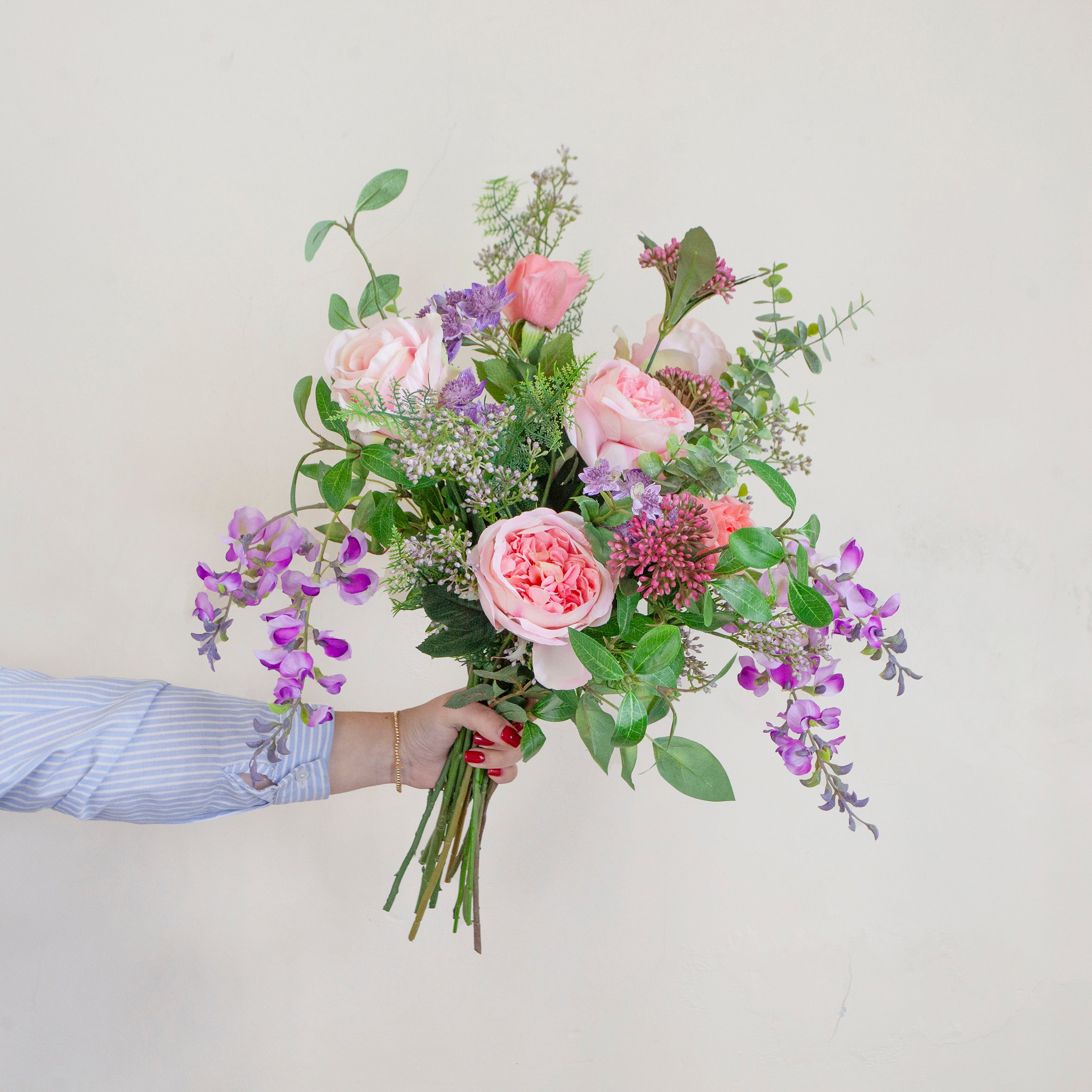 Artificial bouquet of pale pink roses, lavender wisteria, and astrantia with soft greenery,