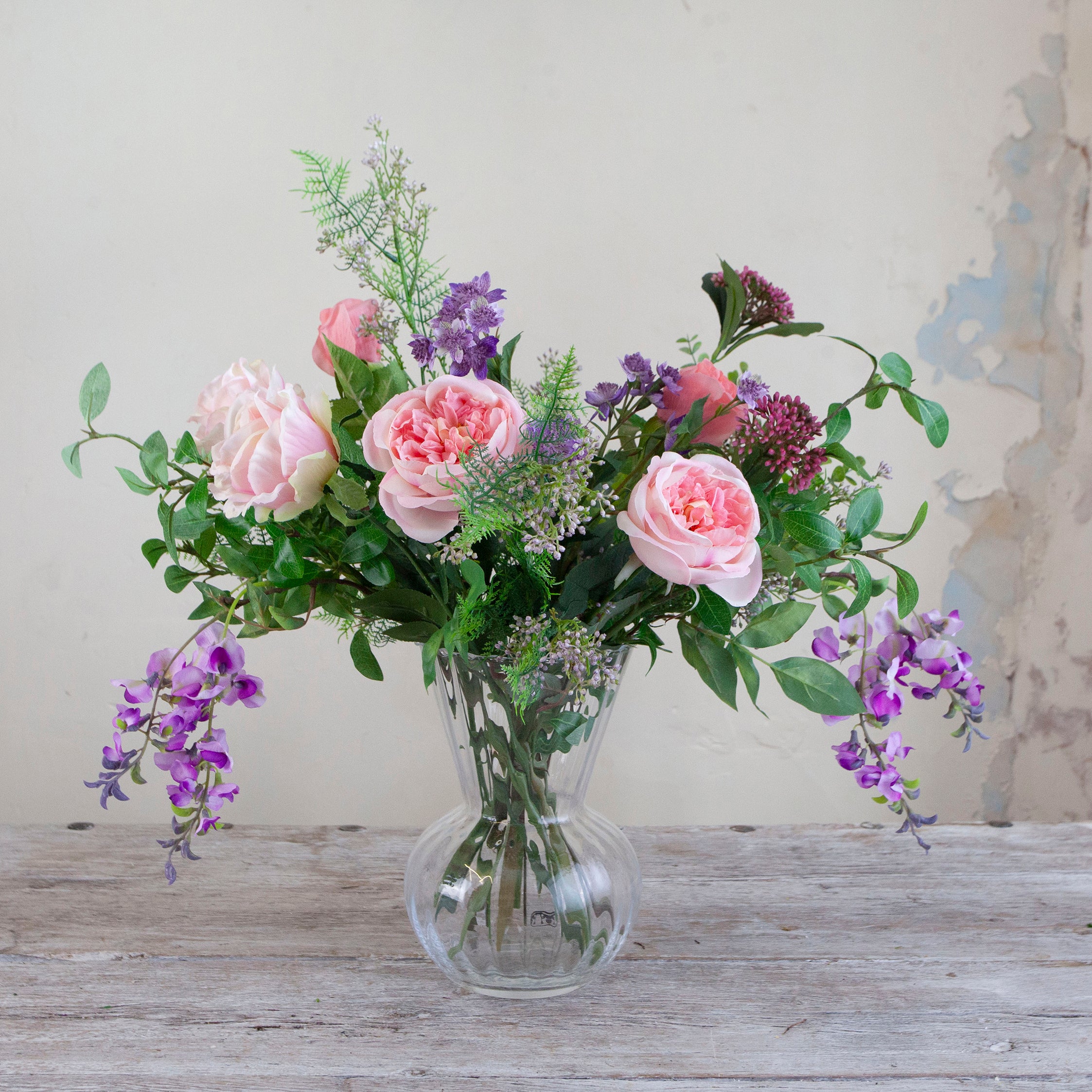 Artificial bouquet of pale pink roses, lavender wisteria, and astrantia with soft greenery,