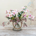 Artificial cosmos flower arrangement featuring soft pink blooms with eucalyptus and flocked greenery, displayed in a medium rope lantern vase