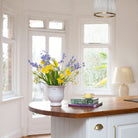 Artificial Spring flower arrangement with daffodils, bluebells and fritillaria in a white aged urn