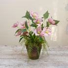 Artficial hellebore flowers arranged in a moss pot with foliage and willow