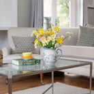 Artificial daffodil and ranunculus flower arrangement in a blue and white hand painted oriental jug