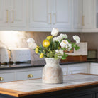 Artificial tulip and ranunculus flower arrangement in a rustic Roman style pot