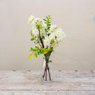 Artificial blossom stems arranged in a clear glass milk bottle vase