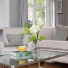 Artificial blossom stems arranged in a clear glass milk bottle vase