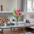 Artificial blossom stems arranged in a clear glass milk bottle vase