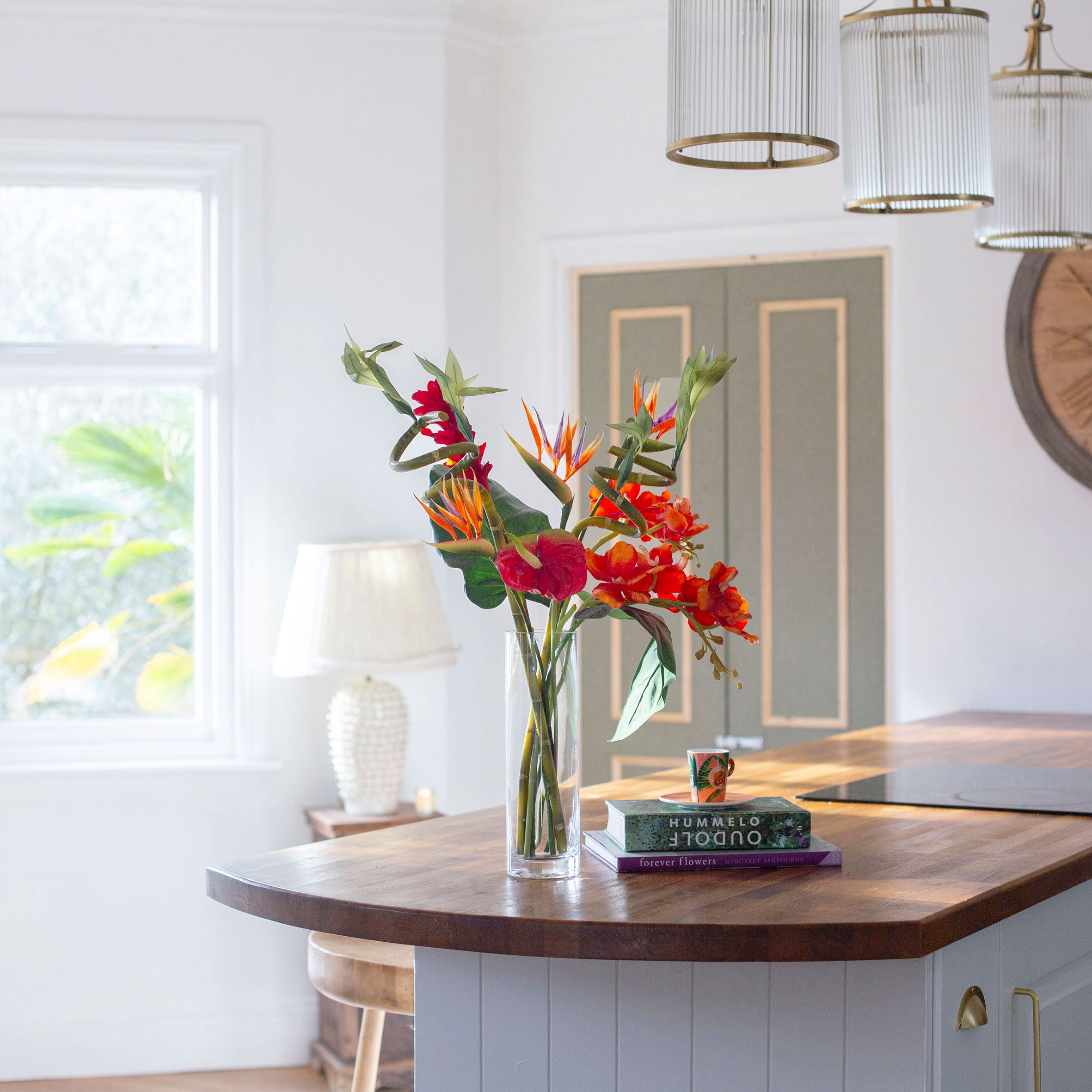 Artificial t ropical flower arrangement with orchids and birds of paradise in a glass cylinder vase