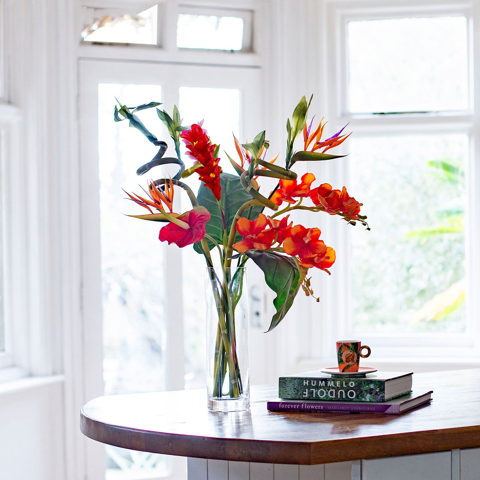 Artificial t ropical flower arrangement with orchids and birds of paradise in a glass cylinder vase