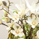 Artificial magnolia flowers arranged in a rustic grey handled planter with birch and willow