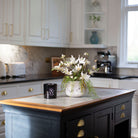 Artificial magnolia flowers arranged in a rustic grey handled planter with birch and willow