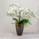 Artificial phalaenopsis orchid and ferns arranged in a tall lotus style pot