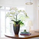 Artificial phalaenopsis orchid and ferns arranged in a tall lotus style pot