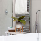 Artificial real touch rubber plant in a grey pot with a natural wooden stand, styled in a modern bathroom.