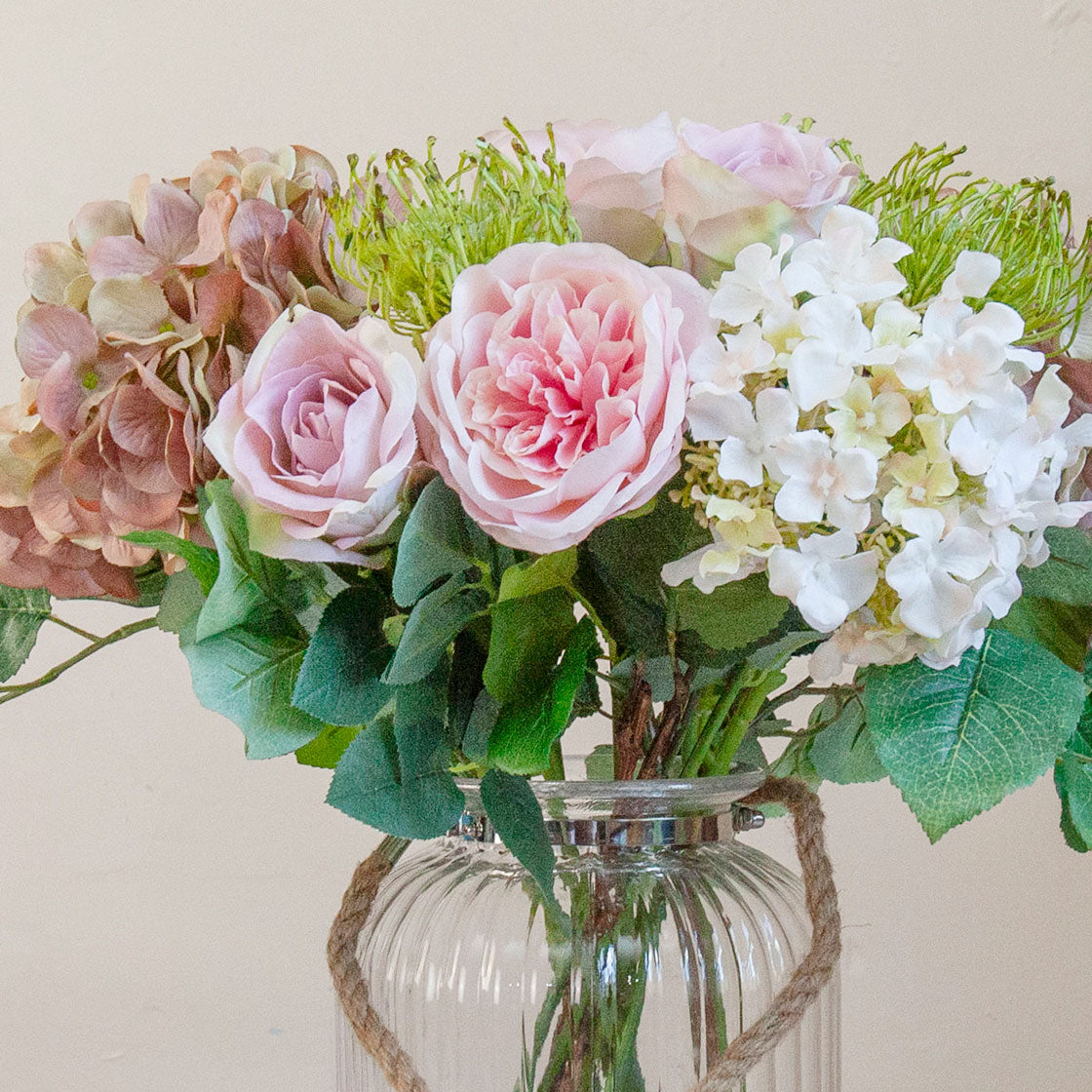 Close-up of an artificial hydrangea, rose and chrysanthemum bouquet in soft pink, white and muted autumn tones.