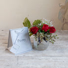 Artificial red roses, mini eucalyptus and gypsophila set in a clear optic glass jar vase with Peony gift bag.