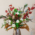 Close-up of an artificial rose and berry arrangement with white roses and rich autumn foliage in a tall bronze geometric pot.